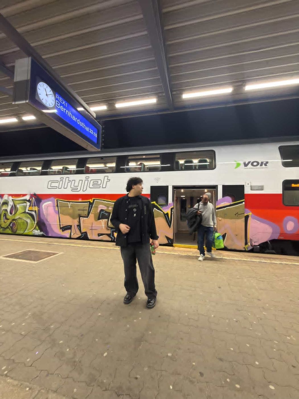 Samuels on a train platform at night next to a graffiti-covered double-decker train