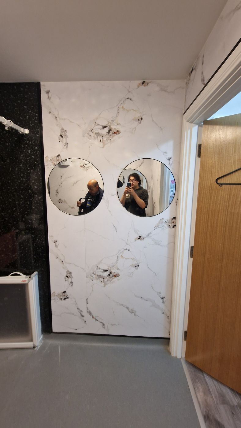 Job E wall 3 after: marble panels with two round mirrors beside the door