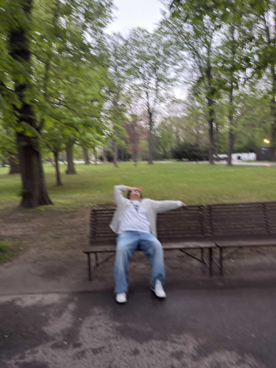 Blurry photo of Samuels lounging dramatically on a park bench