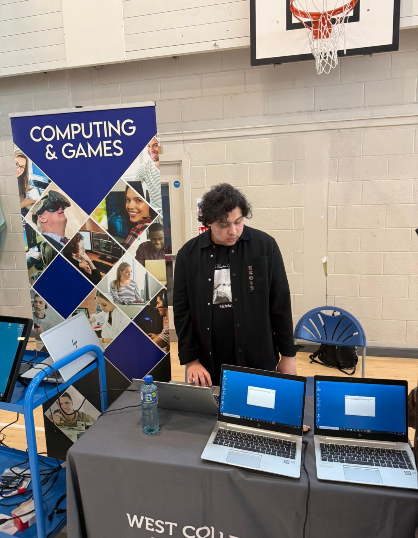 Samuels at a West College Scotland open day stand with laptops, demonstrating cyber security