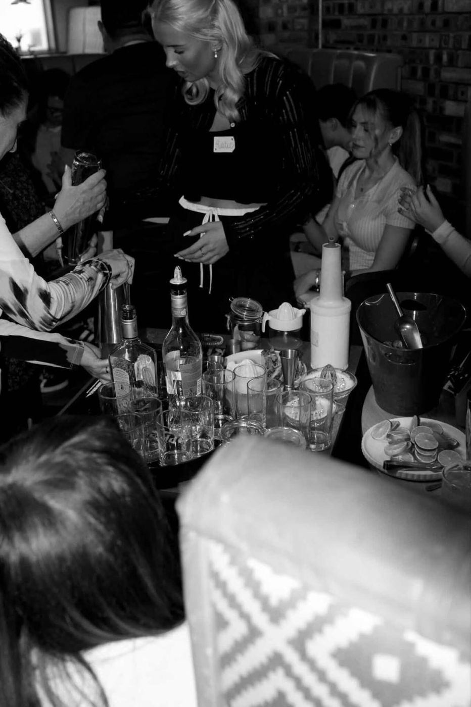 Black and white photo of guests mixing cocktails at a table